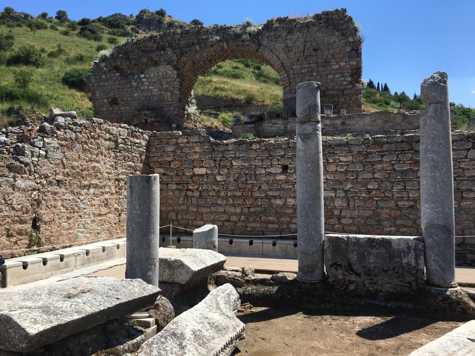 The long row of marble seats in the Roman public latrine at Ephesus, behind standing columns, with a rope strung in front of the seats